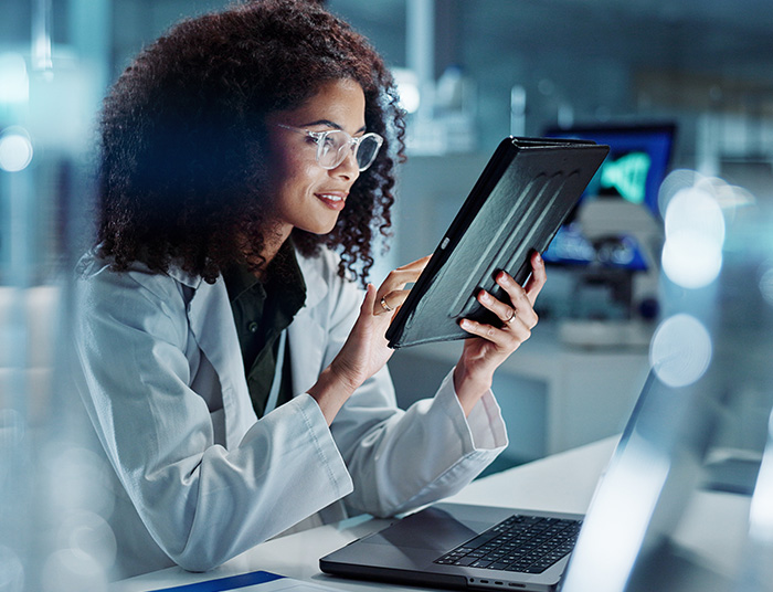 Tablet, laptop and woman scientist in lab working on medical research