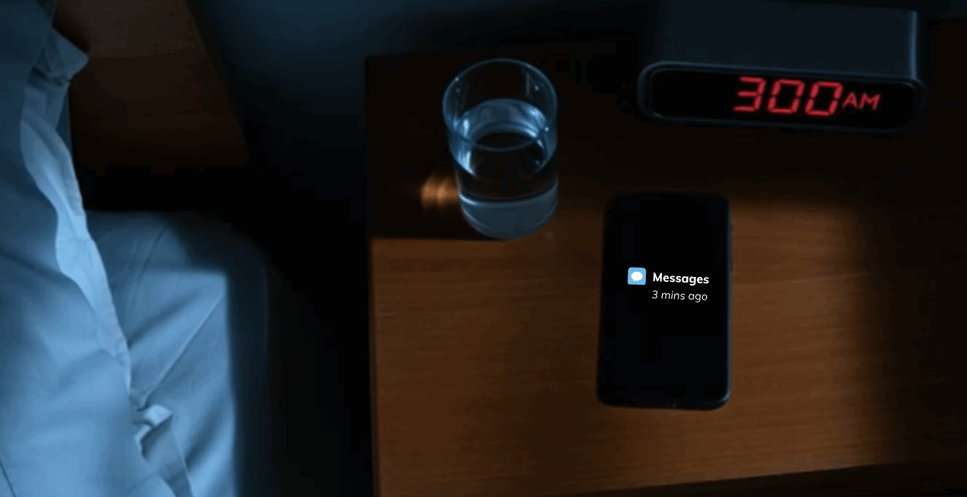 Smartphone glowing with security alert notifications on nightstand at 3 AM with red digital alarm clock showing the time and hand reaching to answer