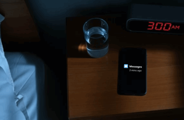 Smartphone glowing with security alert notifications on nightstand at 3 AM with red digital alarm clock showing the time and hand reaching to answer