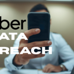 Hand holding smartphone displaying Uber logo with data breach warning alert, illustrating the September 2022 MFA fatigue attack that compromised Uber's internal systems through exhausted contractor approval.